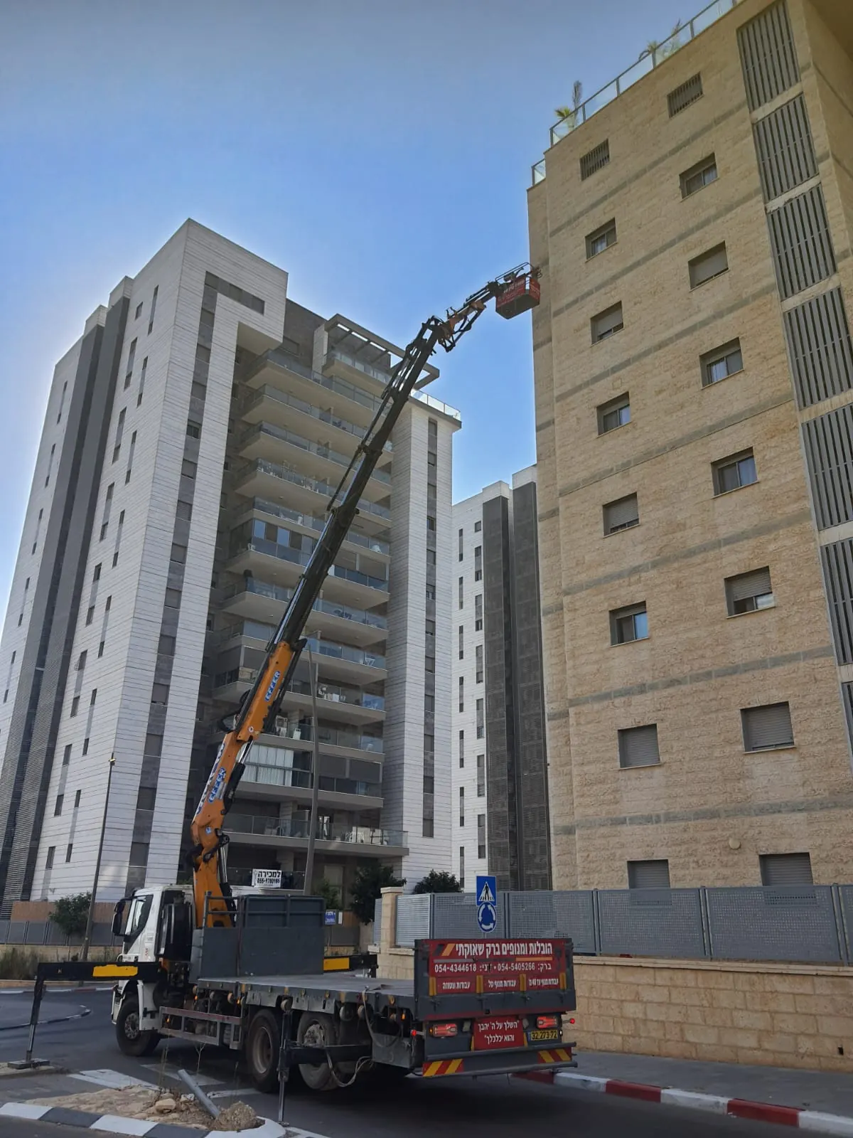 משאית מנוף לצד בניין מגורים גבוה