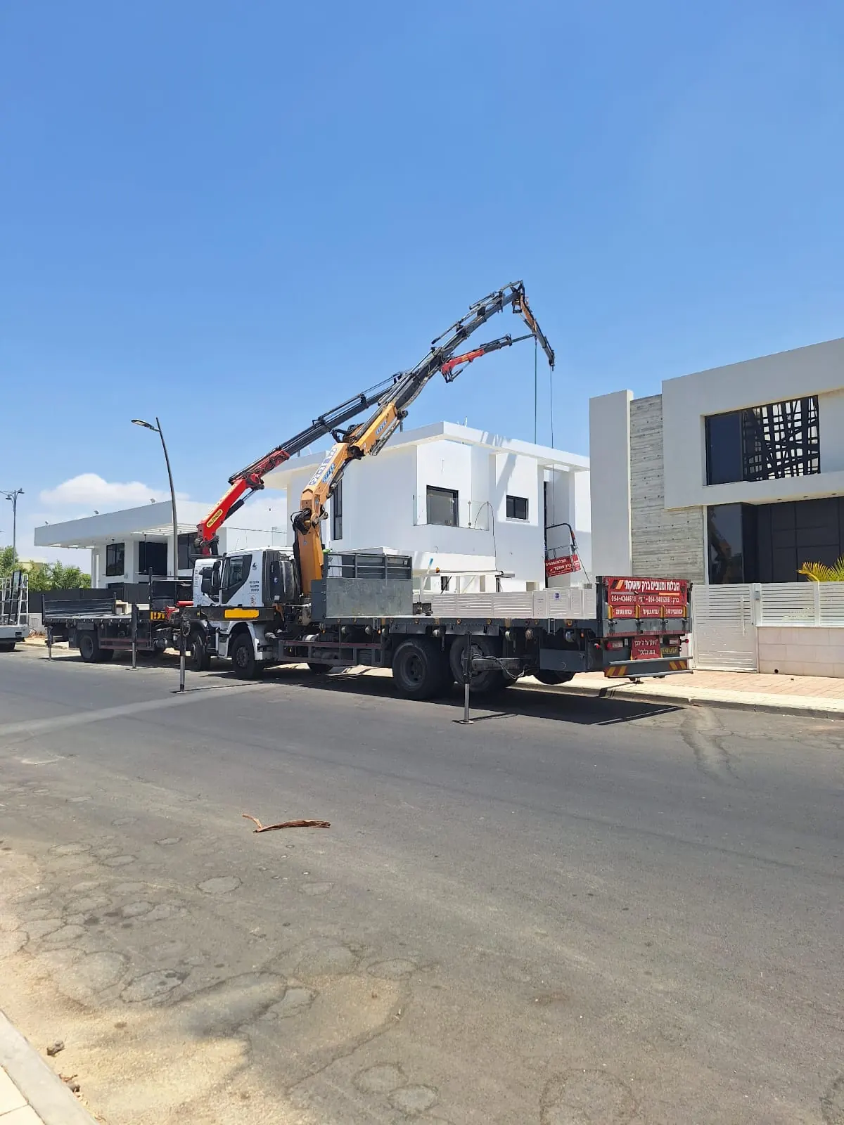 משאיות מנוף באתר עבודה לצד מבנים