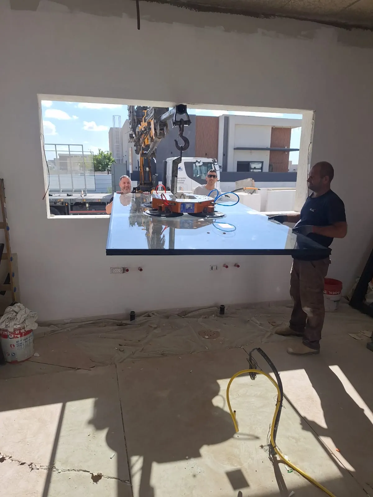 הנפת לוח זכוכית באמצעות ונטוזה ומנוף באתר עבודה